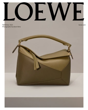 Olive green Loewe Puzzle bag in neutral studio, featuring angular leather panels, top handle, and brand logo in background.