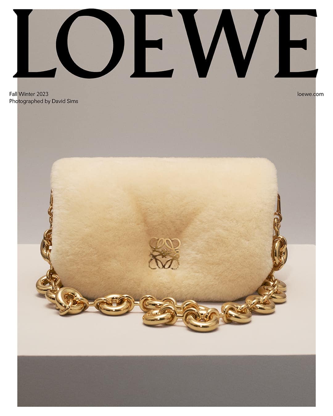 Loewe Fall/Winter 2023 campaign featuring a shearling bag with a chunky chain strap, presented on a white surface against a grey backdrop.