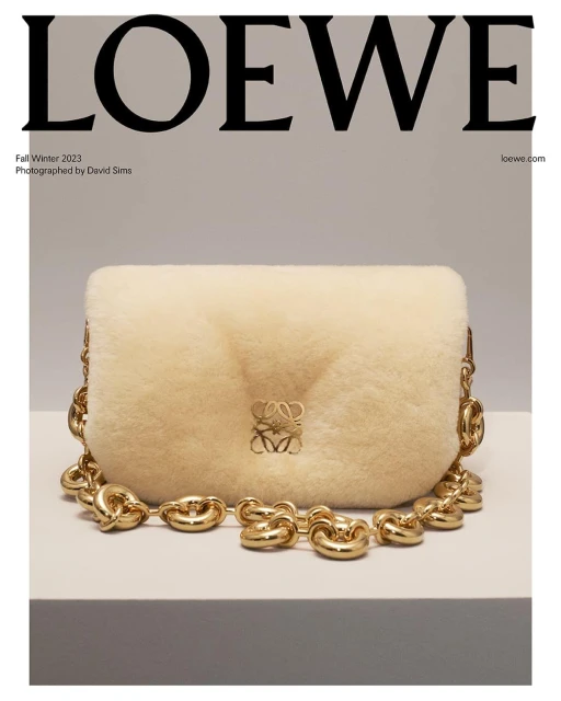 Loewe Fall/Winter 2023 campaign featuring a shearling bag with a chunky chain strap, presented on a white surface against a grey backdrop.
