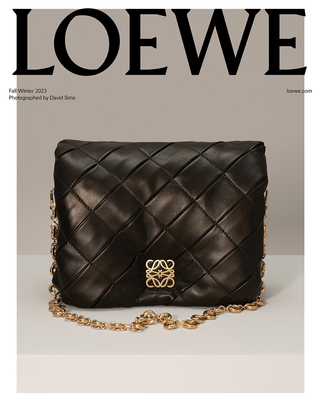 Loewe black nappa leather shoulder bag with chain strap and Anagram logo on a light grey background, studio photography.