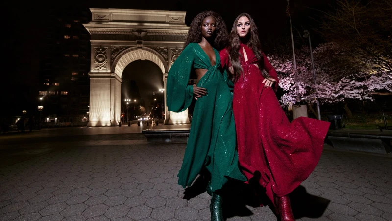Two fashion models in evening gowns pose in front of the Washington Square Arch at night, showcasing a high-fashion aesthetic.