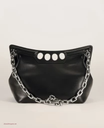 Black leather Alexander McQueen handbag with a chunky silver chain strap and four knuckle cutout holes on a plain white studio background.