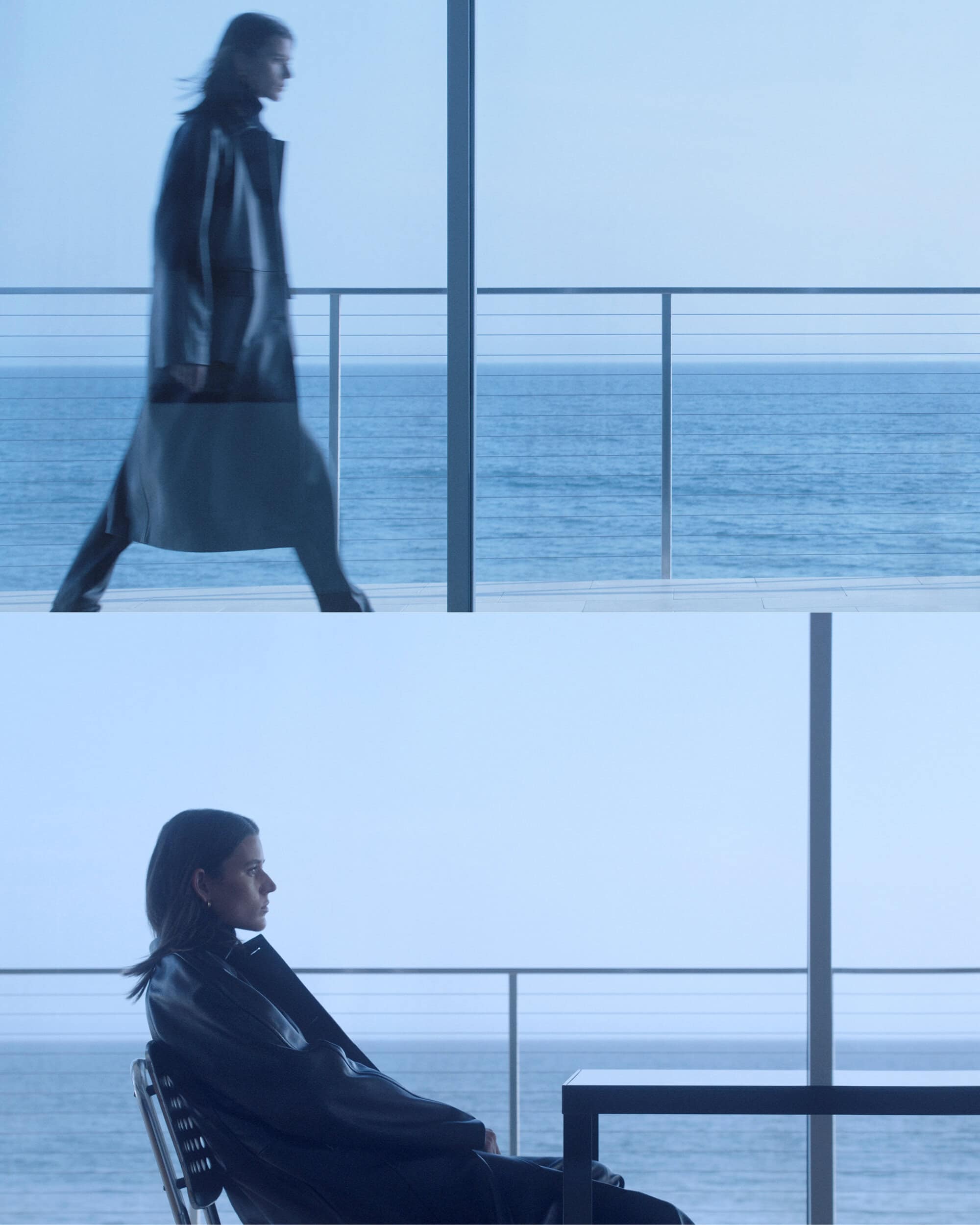 Woman in a long dark coat walks and sits on a chair looking out at the ocean in a cool-toned, minimalist architectural space.