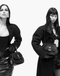 Irina Shayk and a model pose in structured black coats and croc-embossed leather handbags against a pure white studio backdrop.