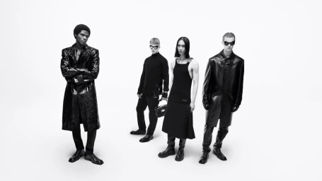 Four male models posing in monochrome black leather coats, knitwear, and kilts against a bright white studio backdrop.