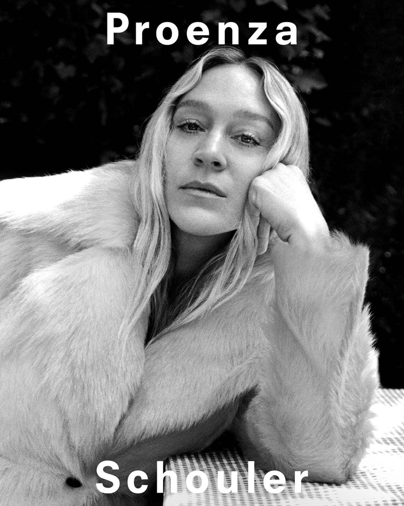 Black and white portrait of a blonde adult woman in a fur coat, seated outdoors, with copy reading 'Proenza Schouler'.