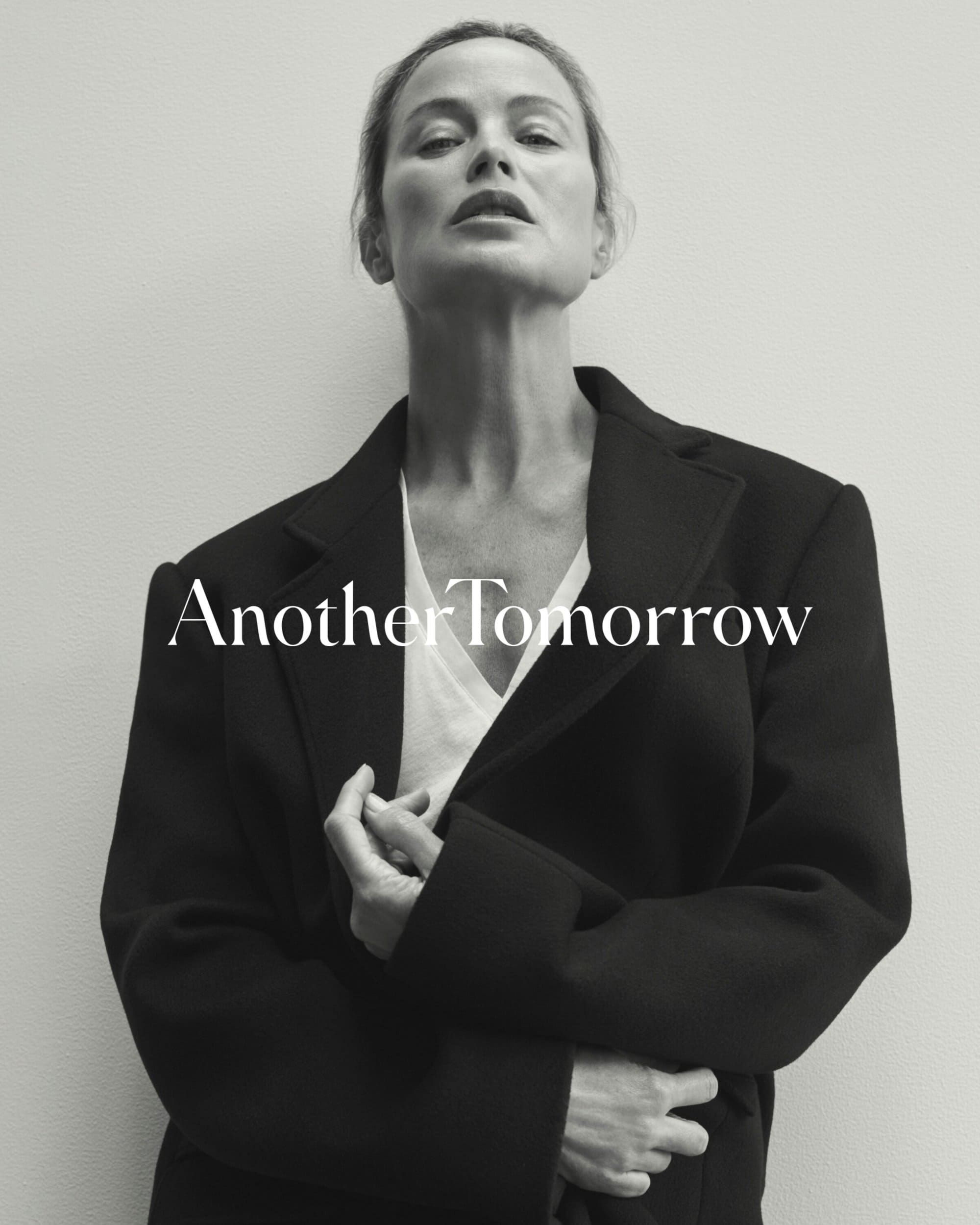 Adult woman in a black jacket and white top poses in front of a gray wall with the text 'Another Tomorrow' overlaid.