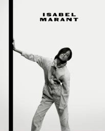 Model wearing a denim jumpsuit posing against a white background with a vertical black stripe for Isabel Marant Fall 2023 campaign.