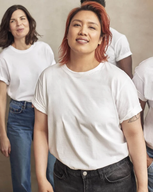 Group of people in white T-shirts and jeans.  Woman in foreground smiles.  Casual fashion clothing.  Diversity in advertising.