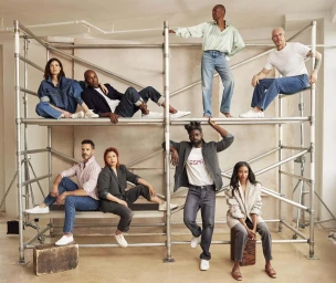 Group of eight models posing across industrial metal scaffolding wearing denim and casual tailored pieces for ESPRIT.