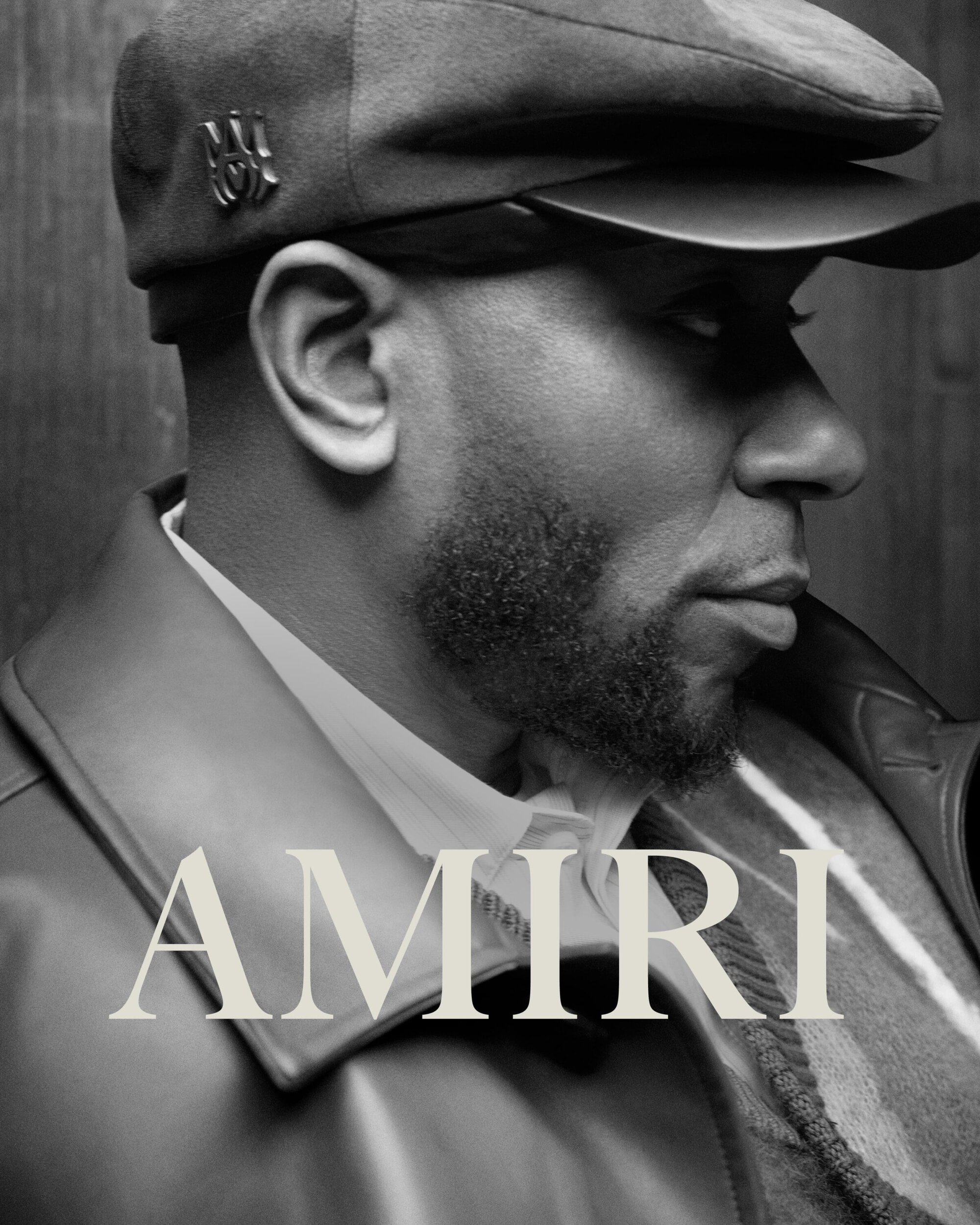 Black and white profile portrait of Yasiin Bey wearing a flat cap and leather jacket for Amiri Fall 2023