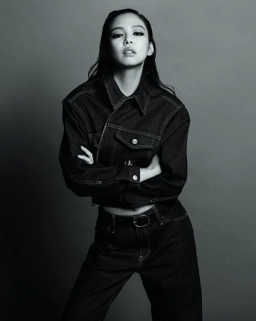 Jennie wearing a dark cropped denim jacket and matching jeans with arms crossed against a seamless studio backdrop.