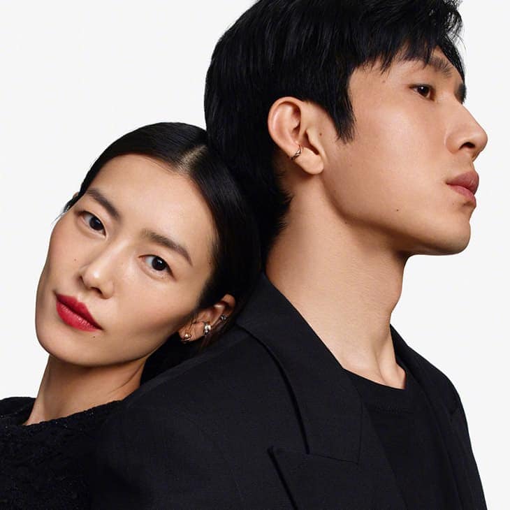 Elegant portrait of an Asian couple in stylish black outfits against a clean white backdrop, emphasizing fashion and beauty.
