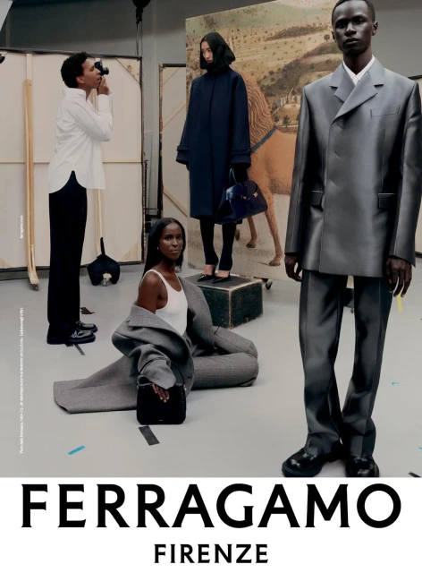 Fashion editorial shot in photo studio featuring four models of different poses wearing grey suit, black coat and white top.