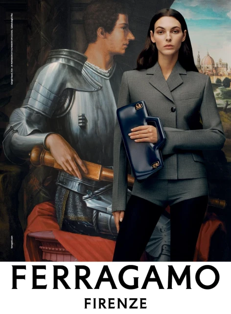A model in a grey suit stands in front of a painting holding a blue handbag, for a Ferragamo fashion advertisement, Florence, Italy.