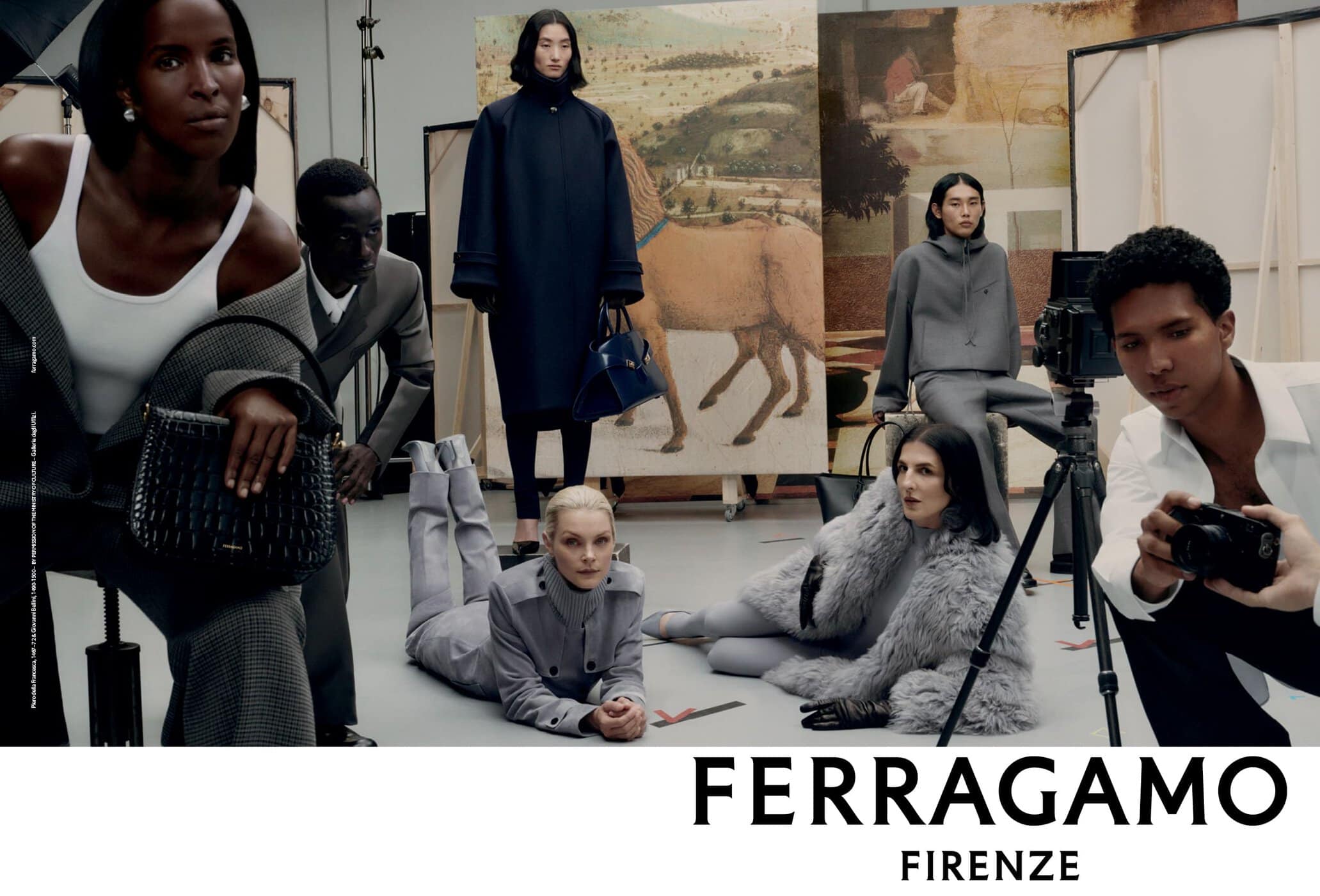 Fashion editorial shot in a studio setting. Several adult models are wearing designer clothing and posing in front of painted canvases.