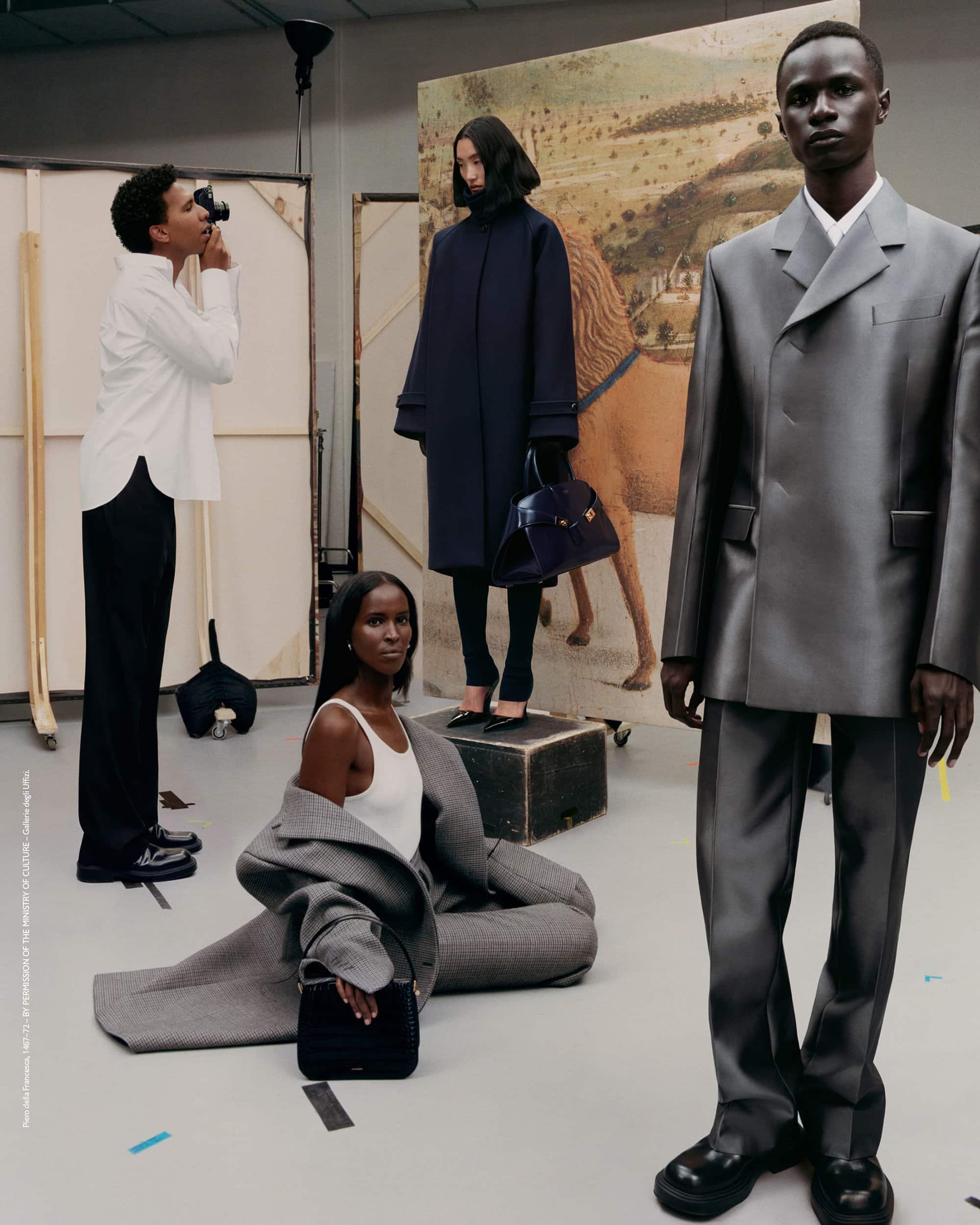 Fashion editorial shot of four dark-skinned fashion models in a photo studio with paintings in the background, wearing clothing.
