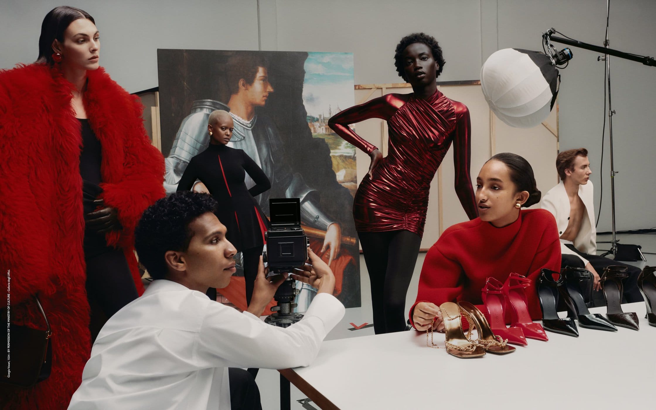 Fashion editorial shoot with diverse models posing in bright outfits, photographer with vintage camera, and table with high heel shoes.