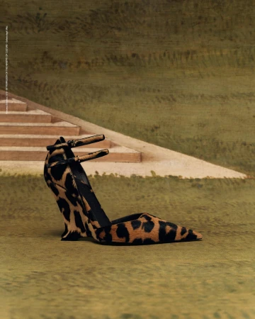 Stylish leopard-print heeled shoe displayed against a soft, muted green background with a suggestion of steps in the upper frame.