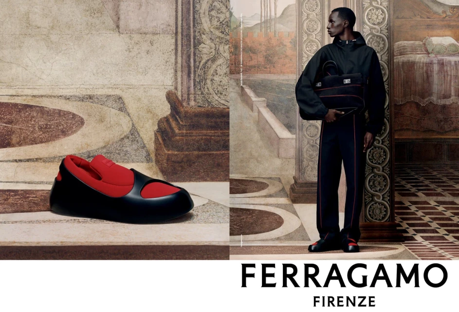 Ferragamo fashion ad: An African male model stands against a painted backdrop holding a bag; a black-and-red shoe sits to the side.