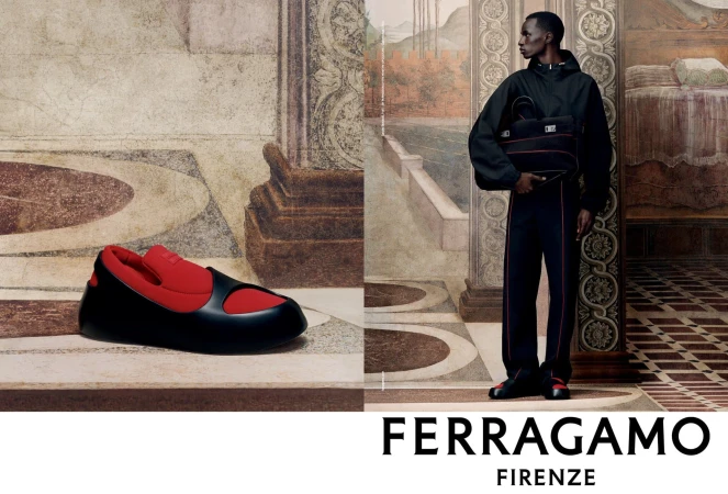 Ferragamo fashion ad: An African male model stands against a painted backdrop holding a bag; a black-and-red shoe sits to the side.