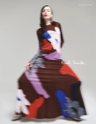 Kiki Willems posing in a brown patterned floor-length dress with motion blur for Paul Smith against a pale backdrop.