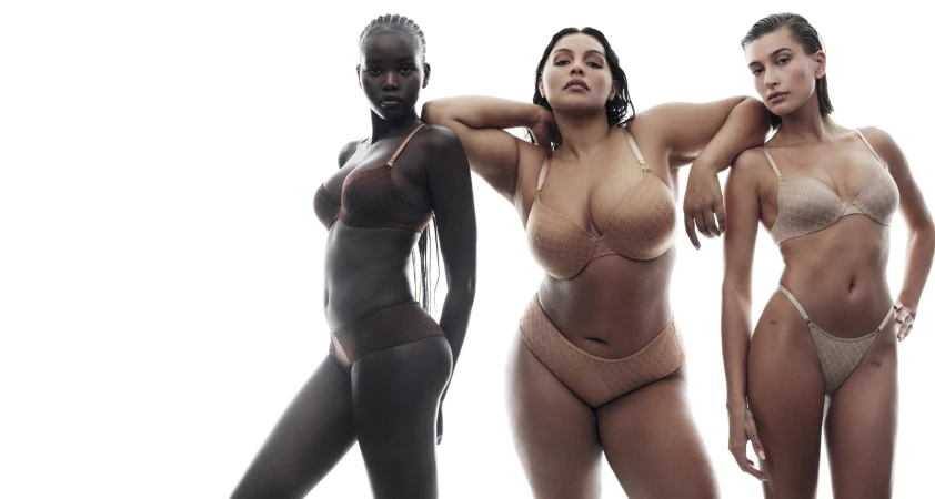 Three diverse women wearing matching lingerie sets in a bright studio setting, showcasing fashion and beauty against a white backdrop.