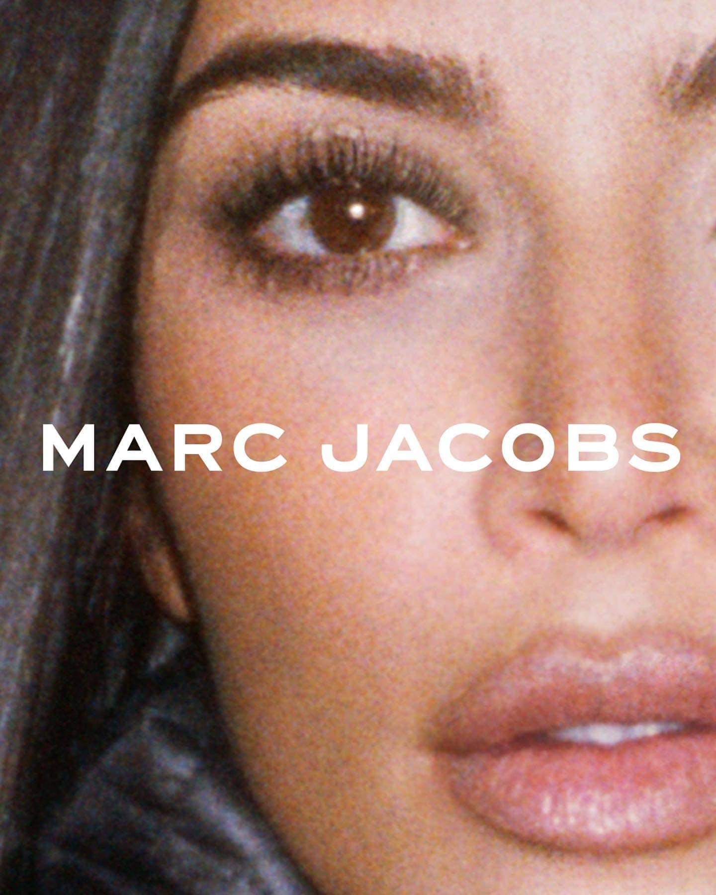 Close-up shot of an adult female's face, featuring her eye, cheek, nose, and lips, with the brand name Marc Jacobs appearing on the left.