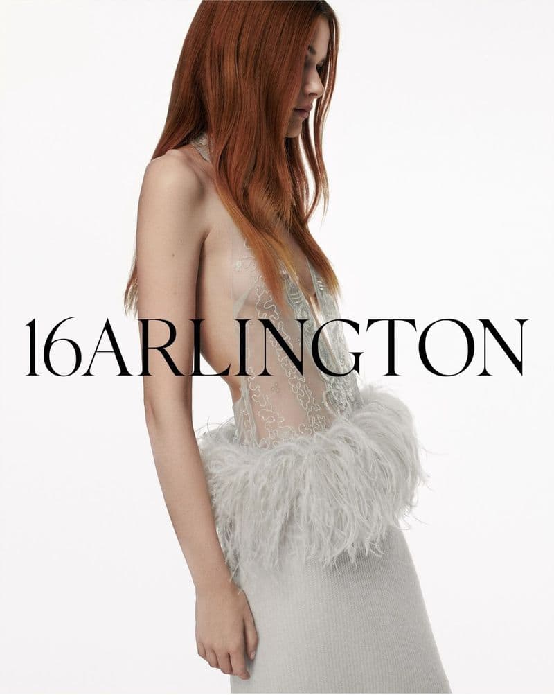 Fashion model showcases a light grey dress with feather embellishments against a clean white backdrop, highlighting the dress's design.