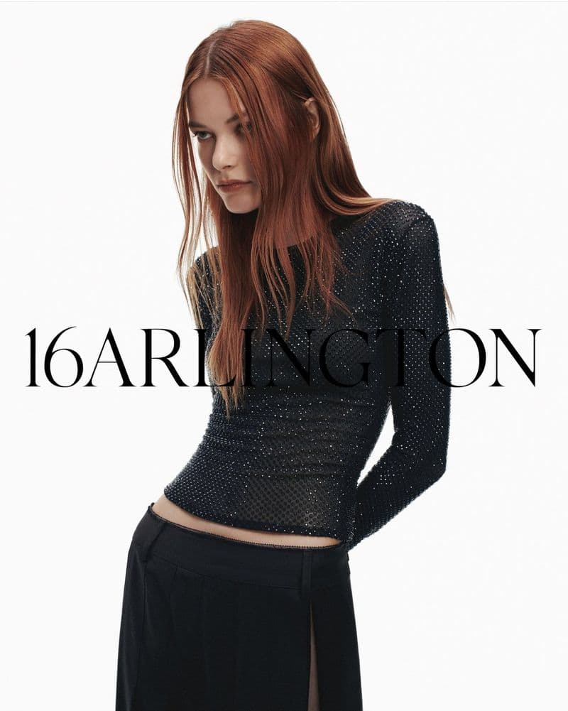 Fashionable woman in black long-sleeve beaded top and skirt posing against white background, advertising 16 Arlington brand.