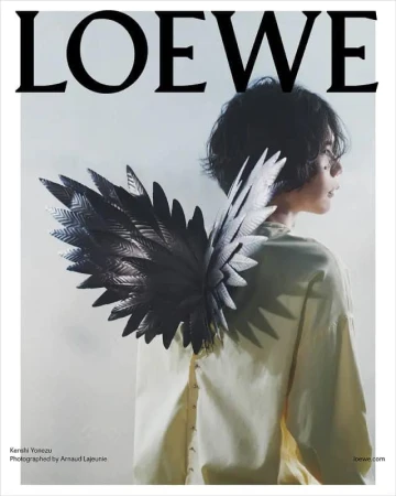 Fashion editorial featuring a young adult with dark hair, light olive button-down shirt, and metallic feather wing accessory.