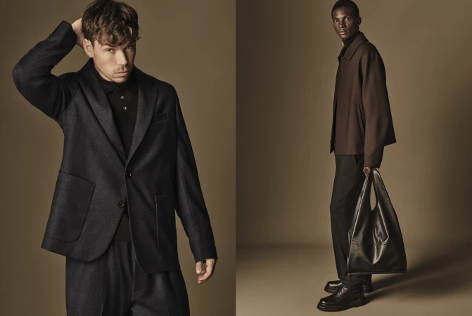 Two adult men in formal wear pose against a neutral backdrop in a studio setting; one carries a large black leather bag. 