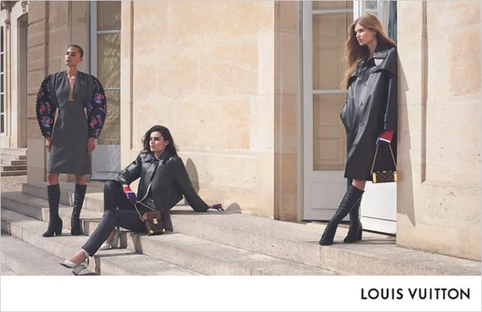 Three fashion models pose outside a building, showcasing clothing and accessories. Two wear knee-high boots, one is seated on stairs.