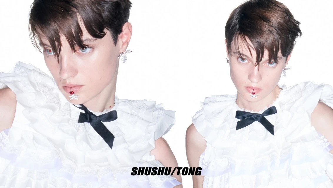 Two portraits of a young adult with short dark hair wearing a white ruffled dress with a black bow and lip jewelry against a white background.