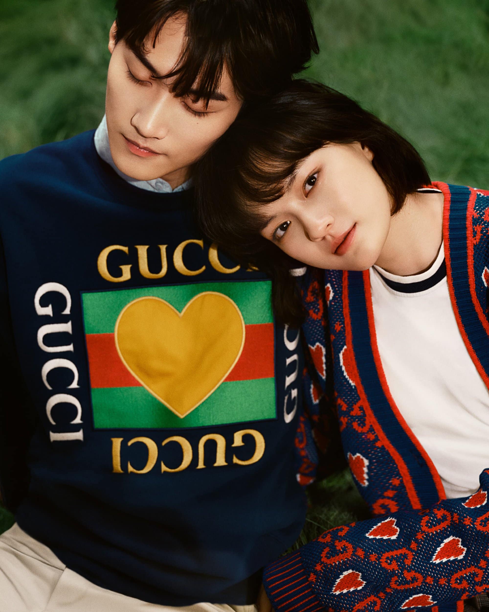 A close-up studio shot features a young adult couple in Gucci sweaters posing intimately against a soft green backdrop, showcasing fashion.