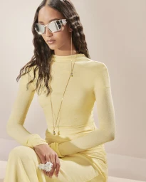Model Mona Tougaard wearing futuristic silver sunglasses and a pastel yellow long-sleeve dress for Givenchy Fall 2023.