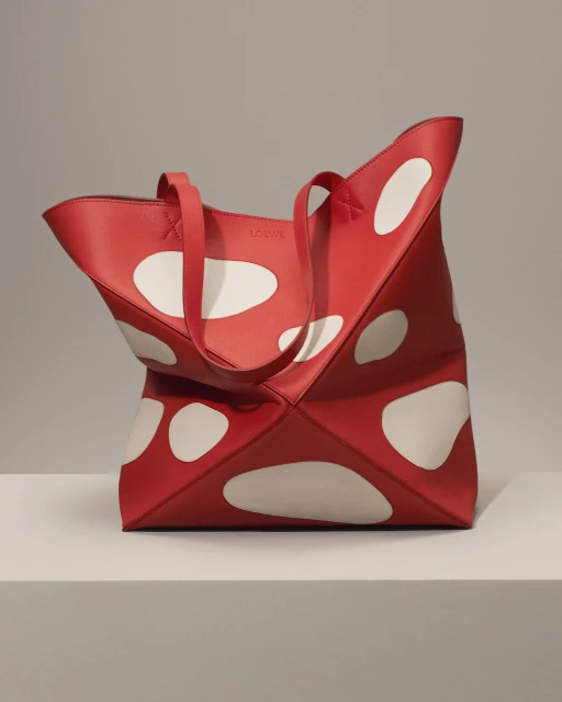 Stylish red leather tote bag with white polka dots. Modern design for fashion, shopping, or everyday use on a neutral background.