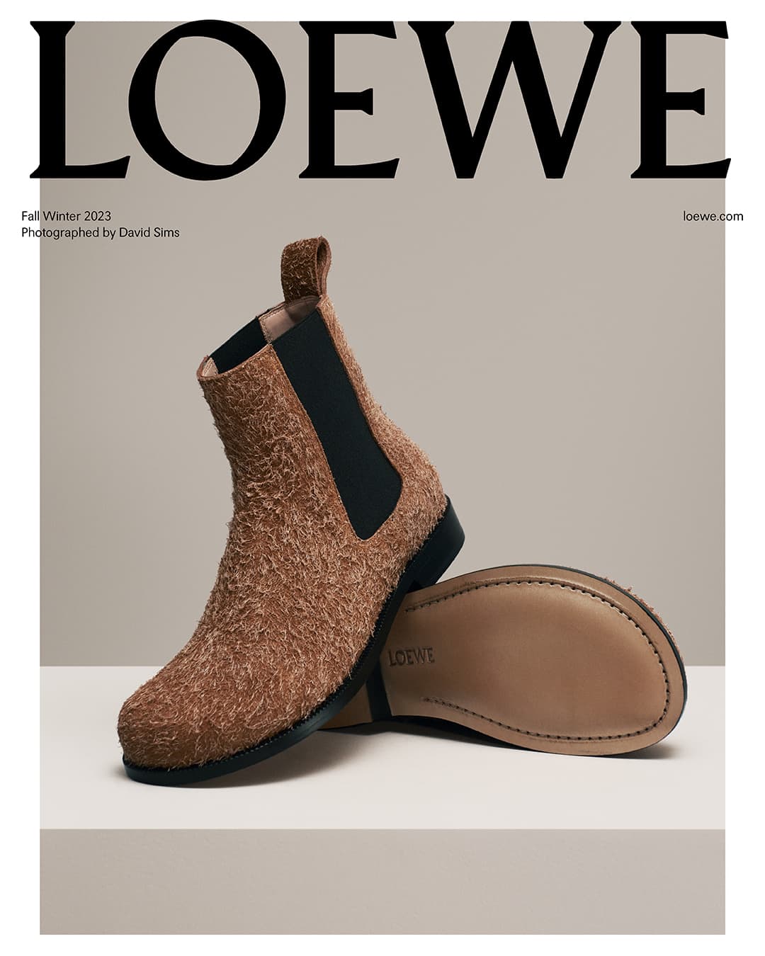 Loewe fall/winter 2023 fashion ad featuring a brown suede Chelsea boot with a black elastic side panel on a cream surface.