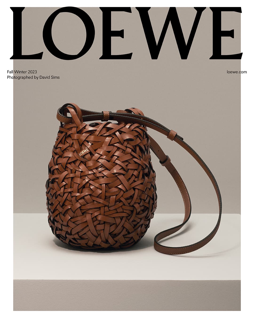 Loewe woven bucket bag in brown leather displayed against a neutral backdrop, with brand logo and Fall/Winter 2023 text.