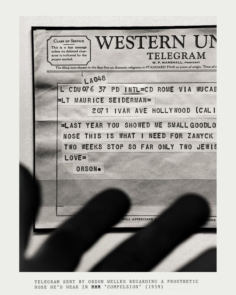 Close-up of a Western Union telegram in black and white, featuring a message from Orson Welles, partially obscured by shadowy fingers.