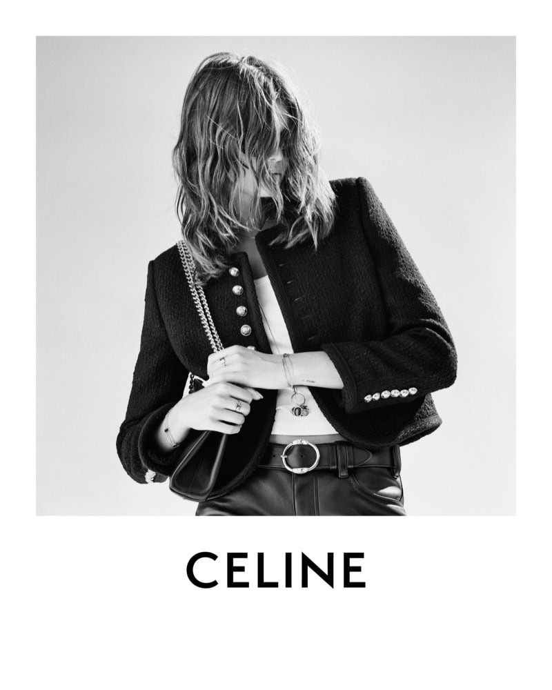 Black and white portrait of a woman wearing a black jacket and leather pants, holding a black purse. The brand CELINE is at the bottom.