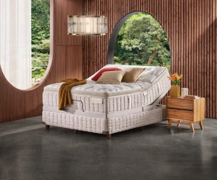 Adjustable bed with tufted beige base and pillows against a wood slat wall and large arched window for Domayne Mattress Project