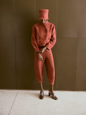 Model Ajok Madel wearing a rust orange tweed jacket, matching trousers, and hat for Harper's Bazaar España