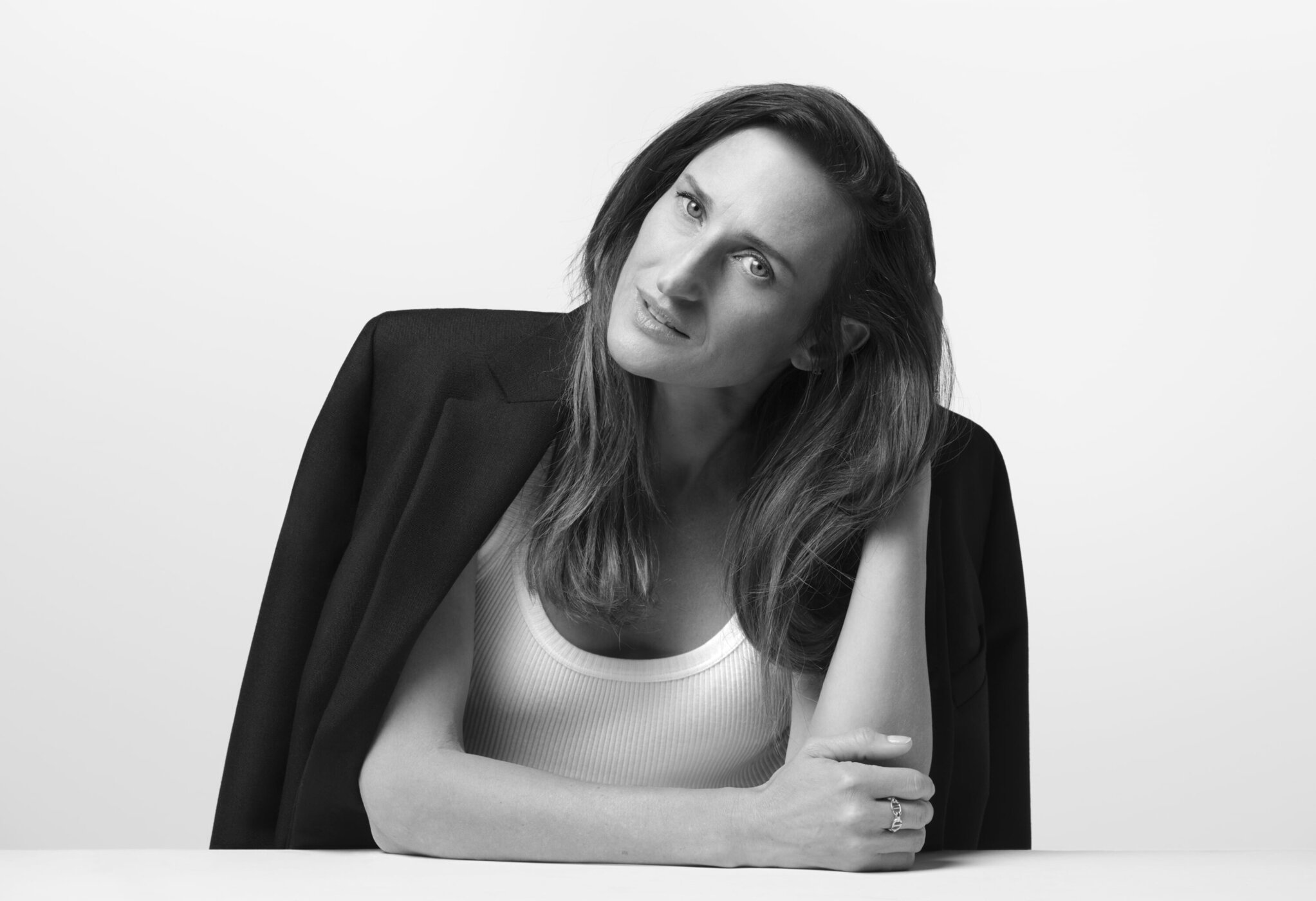 Black and white portrait of an adult female with long hair wearing a white top and black blazer against a white background.