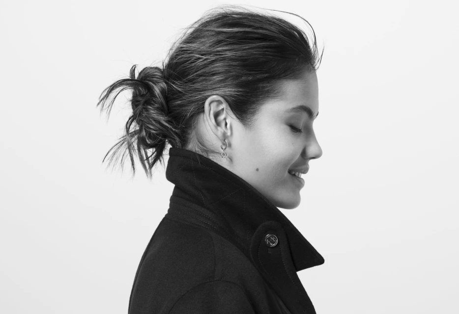 Black and white portrait of a woman in a dark coat with her hair pulled back, smiling slightly against a plain white background.