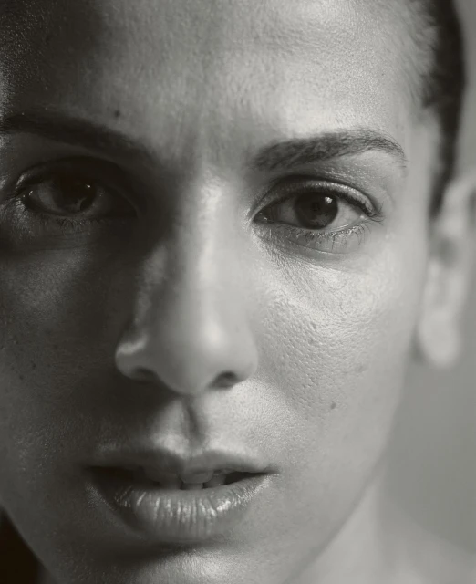 Striking black and white portrait of an adult woman, captured in a close-up shot that highlights her facial details and intense gaze.