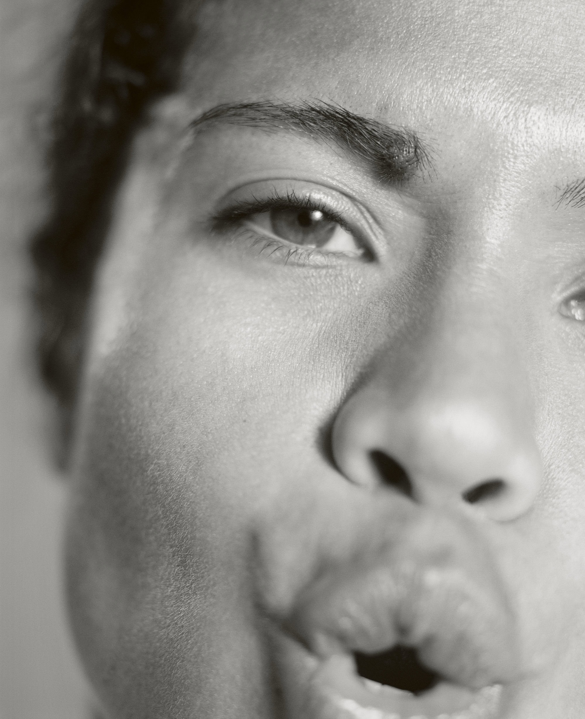 Close-up black and white portrait of an adult female with her mouth open and puckered lips, looking directly at the camera.