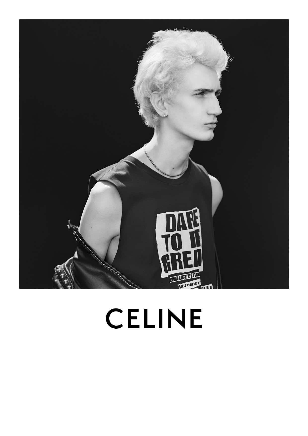 Black and white portrait of a young adult male with light blonde hair wearing a graphic tee and leather jacket, in a studio setting.