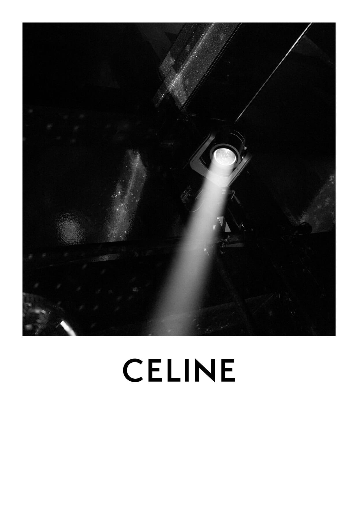 Black and white photo of a stage spotlight shining on a dark background with the 'CELINE' logo visible at the bottom.