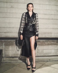 Elise Crombez wearing a hybrid tweed and black leather biker jacket with a high-slit leather skirt against a concrete wall.